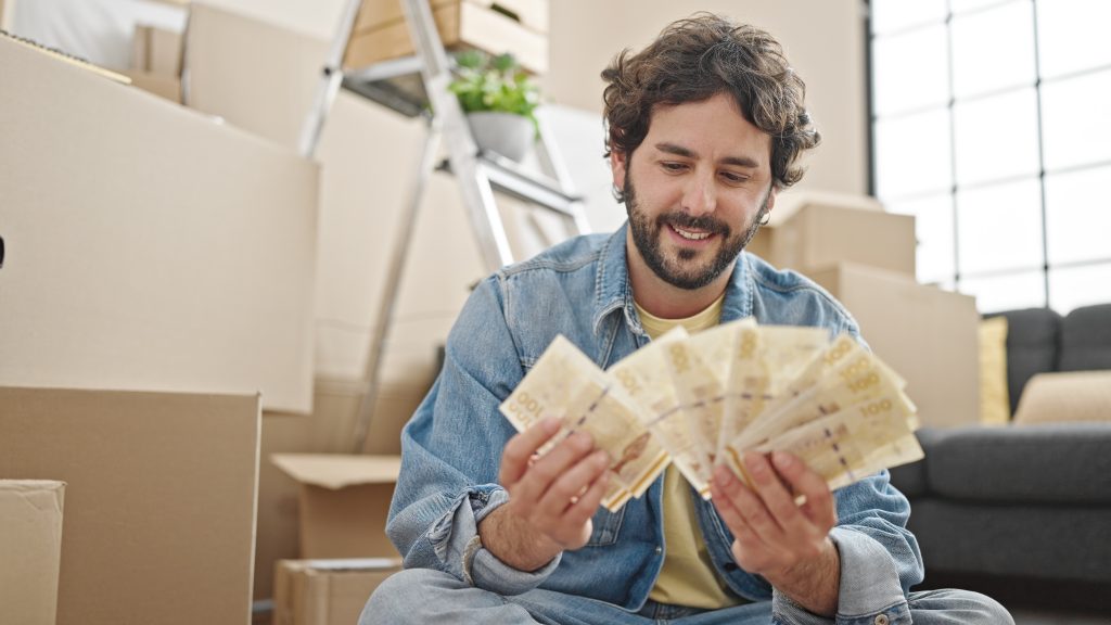 young hispanic man counting denmark krone banknotes sitting floor new home x