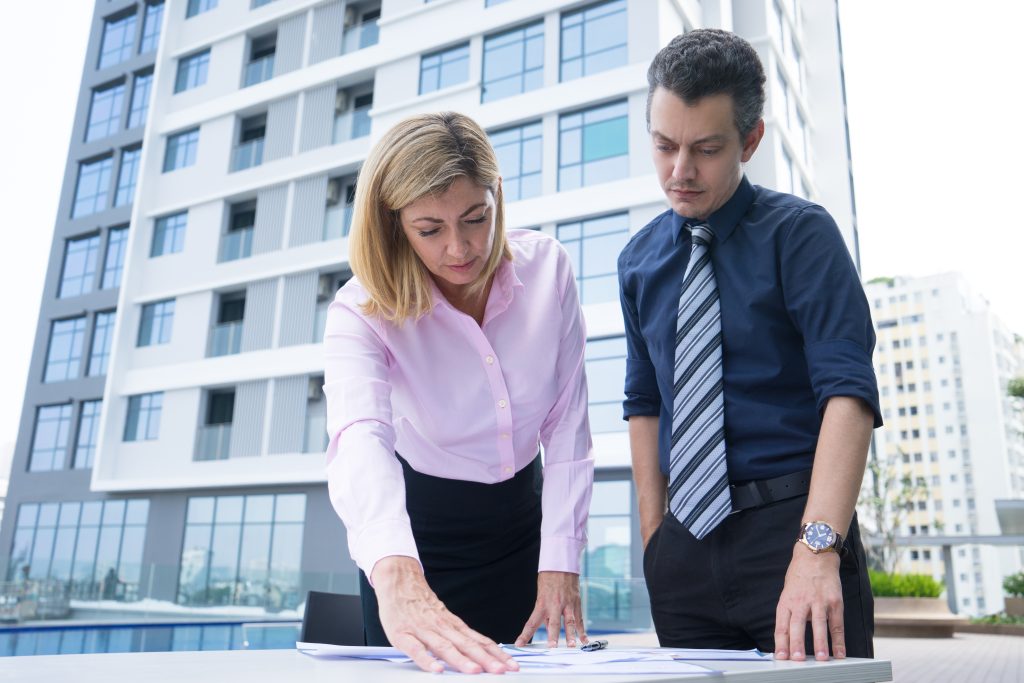 concentrated thoughtful business colleagues standing near table analyzing documents x
