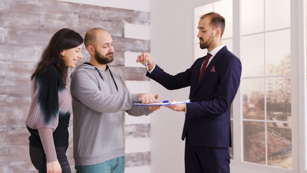 young couple becoming homeowners after signing documents with real estate agent business suit agent giving keys couple x