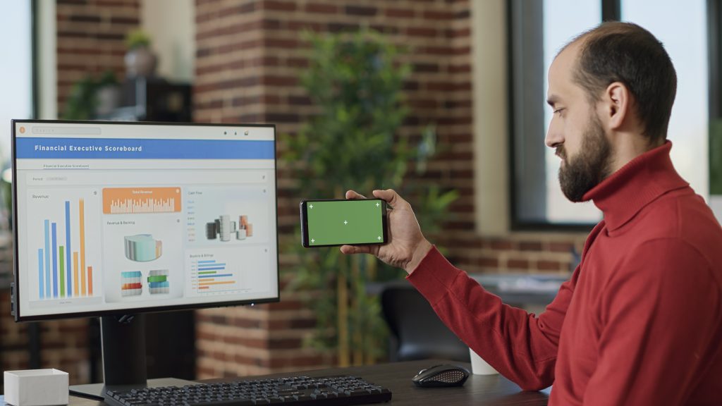 male worker holding smartphone with horizontal green screen business office young adult working with blank chroma key isolated template with mockup background mobile phone display x
